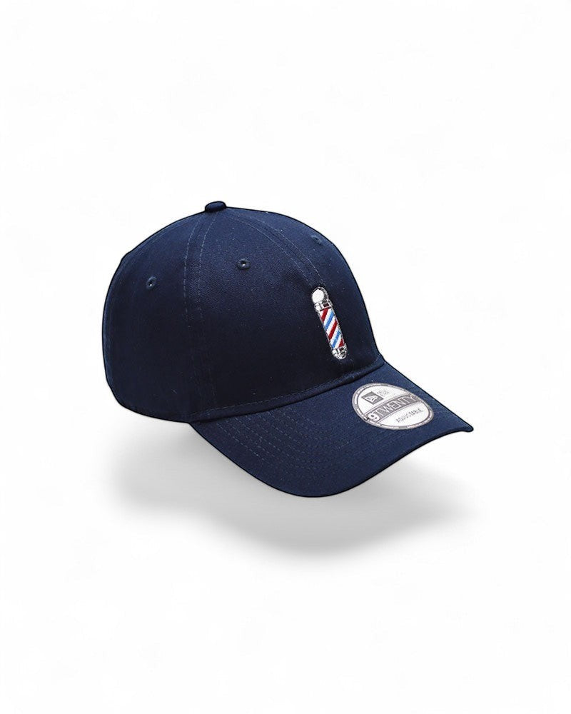 V's Barbershop navy baseball cap with embroidered barber pole logo on front. One size fits all.