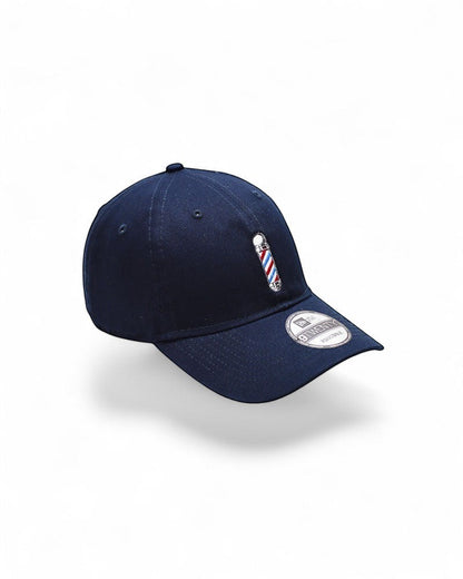 V's Barbershop navy baseball cap with embroidered barber pole logo on front. One size fits all.