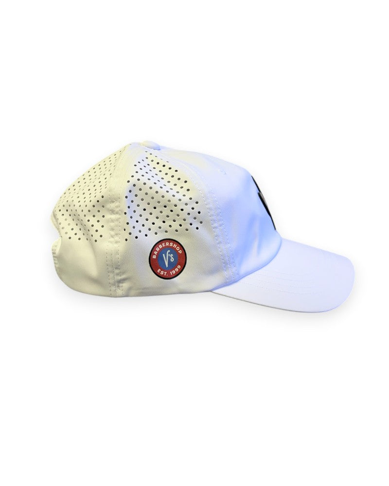 V's Barbershop white dad hat with perforated side panels and a circular logo patch on the side.